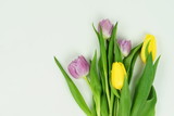Fototapeta Tulipany - Flowers background. Bouquet of purple and yellow tulips flowers on pastel violet color backdrop top view. Copy space.Holiday concept