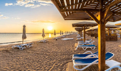 Landscape with sunbeds and umbrella on the Red Sea beach at sunrise in Hurghada, Egypt