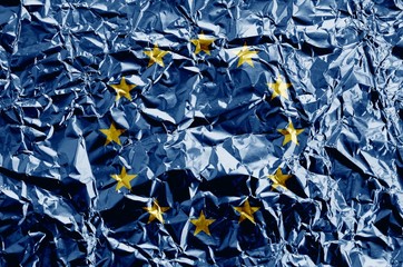 Wall Mural - European union flag depicted in paint colors on shiny crumpled aluminium foil closeup. Textured banner on rough background