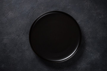 Black plate on black stone table top view.