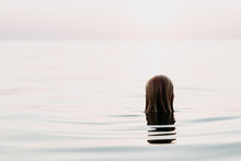 Woman Floating In The Sea Looking In Sunset