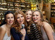 © Syda Productions - female friendship, leisure and luxury concept - happy women with microphone singing karaoke over restaurant or wine bar background