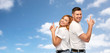 © Syda Productions - relationships and people concept - portrait of happy couple in white t-shirts making gun gesture over blue sky and clouds background
