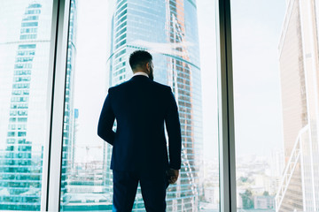 Confident employee looking out window on cityscape