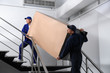 © New Africa - Professional workers carrying refrigerator on stairs indoors