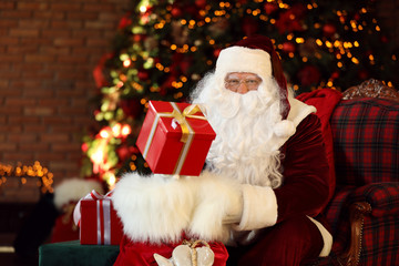 Canvas Print - Santa Claus with gift sack near Christmas tree indoors