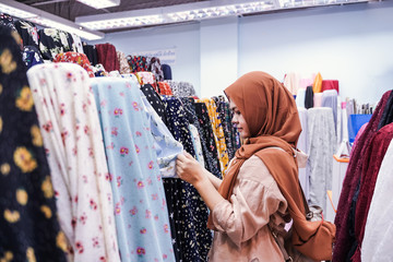 Wall Mural - Muslim woman pick a roll of cloth at the fabric mall, They sell Muslim fashion online and in-store in retail.