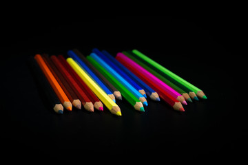 GROUP OF COLORED PENCILS ON BLACK BACKGROUND