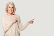 © fizkes - Happy elderly woman showing to empty space for copyspace