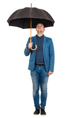 Full length portrait of confused businessman standing under open umbrella looking up perplexed isolated over white background.