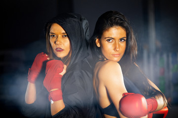 Two beautiful female boxer in the gym at night preparing for a fight