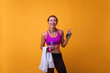 © ClaudiK - Happy young woman in sports clothing smiling. Muscular fitness model on yellow background looking away at copy space. Horizontal.
