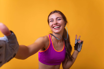 Image of a positive young brunette sports fitness woman posing isolated over white wall background take selfie by camera showing peace gesture.Attractive girl making a selfie after her exercise.