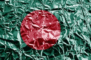 Bangladesh flag depicted in paint colors on shiny crumpled aluminium foil closeup. Textured banner on rough background