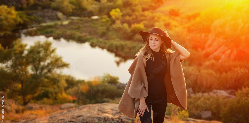 Attractive girl with long blonde hair in black hat and on a background ...