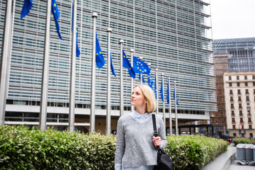 A young woman stands against the backdrop of the European Commission headquarters in Brussels, Belgium