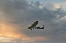 Cessna Plane Flying At Sunset In The Clouds