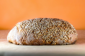 Big fresh bread loaf covered with sunflower seeds, bakery or pastry concept, brown organic bread