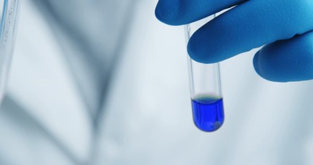Wall Mural - close-up shot with hitting laboratory equipment. blue liquid falling pipette in glass test tube.