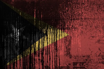 Wall Mural - Timor Leste flag depicted in paint colors on old and dirty oil barrel wall closeup. Textured banner on rough background