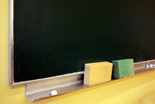 Chalk And Sponges On The Tray Under An Old Green Chalkboard
