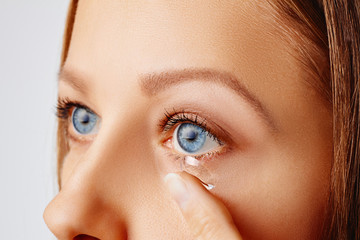 Wall Mural - Young woman puts contact lens in her eye. Eyewear, eyesight and vision, eye care and health, ophthalmology and optometry concept