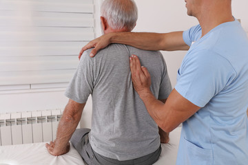 Wall Mural - Senior man with back pain. Spine physical therapist and paient. Chiropractic pain relief therapy.