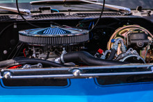 Blue Classic Muscle Car Under Hood Close Up, Big Chrome Round Air Intake Filter, Engine And Radiator Parts, Tubes, Wires, Pipes, Brake Vacuum Servo