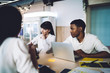 © BullRun - Concentrated multiracial colleagues discussing project and using laptop in meeting room