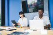 © BullRun - Content multiracial coworkers using laptop and tablet at meeting