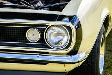 old vintage American muscle cream white car half front, right side, open hood engine parts view, close up on headlights light lamp, chrome bumper