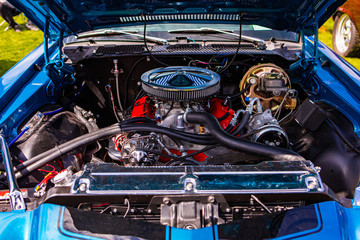 Blue classic muscle car, Open hood close up on red engine, Big chrome round air intake filter, tubes, wires, pipes, brake vacuum servo, other parts