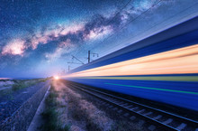 High Speed Train In Motion And Milky Way At Starry Night. Industrial Landscape With Sky And Stars Over Blurred Modern Passenger Train And Railroad. Railway Station And Space. Technology And Nature