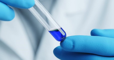 Wall Mural - close-up shot with hitting laboratory equipment. blue liquid falling pipette in glass test tube.