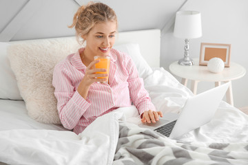 Poster - Morning of beautiful young woman with laptop drinking juice in bed