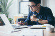 © panitan - contact Asian businessman professional people thinking while working writing information documents in home offices at desk with computer,laptop,cell phone,business report chart