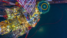 Aerial View Construction Offshore Jack Up Rig Drill At Night, Offshore Crane Crude Oil Rig Drilling Platform.