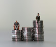Miniature people in piles of coins of different heights. The concept of discrimination in employment.