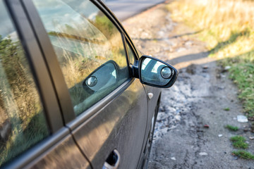 rear view mirror of a brown car standing on the road