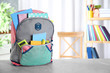 Stylish backpack with different school stationery on table indoors. Space for text