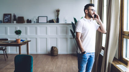 man looking out window and talking on phone at home