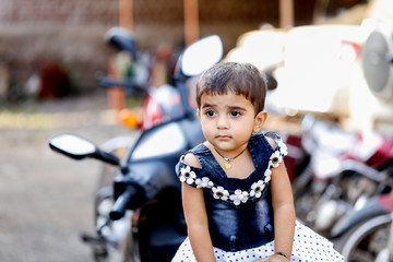 Poster - cute Indian baby child girl sitting on bike 