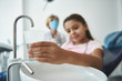 © Yakobchuk Olena - Grinning young girl is holding glass with water at dentist