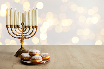 Wall Mural - delicious doughnuts near candles in menorah on white background with bokeh lights on Hanukkah