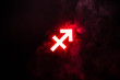 red illuminated Sagittarius zodiac sign with smoke on background