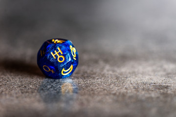Blue Astrology Dice with symbol of the planet Uranus on grey background