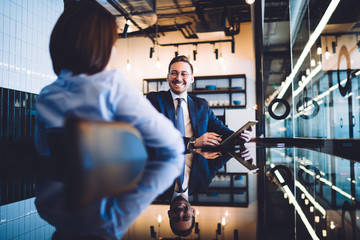 Sticker - Cheerful colleague using tablet and talking to colleague in office