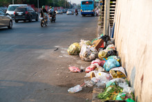 Pile Of Garbage Bags And Messy Trash On Street Sidewalk With Traffic On Background In Hanoi, Vietnam