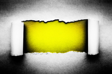 Wall Mural - A hole in vintage paper with torn edges close-up with a yellow vibrant color background inside.