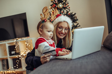 Woman and baby online shopping. Close up of a young woman and her baby buying presents online.